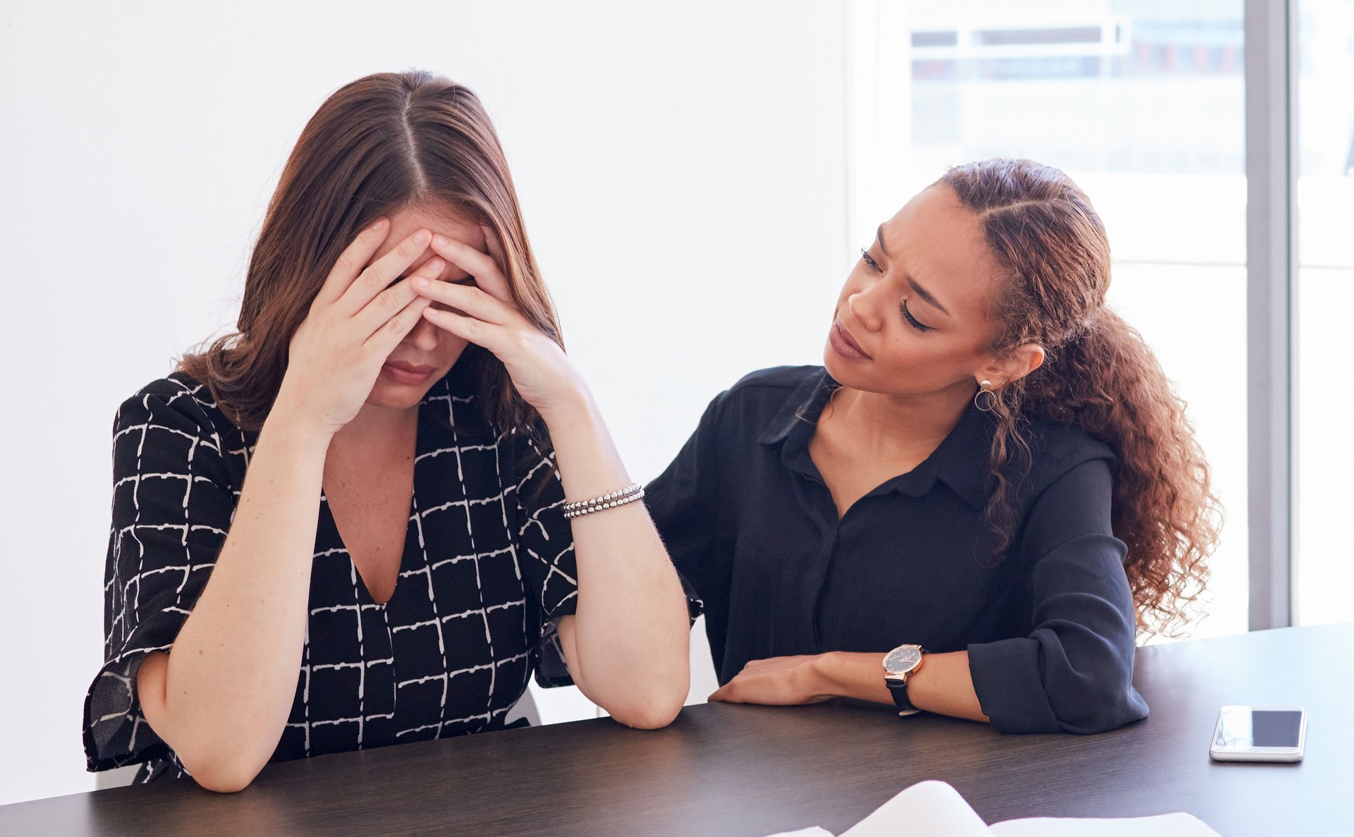 Shot of a young businesswoman in distress being comforted by her coworker