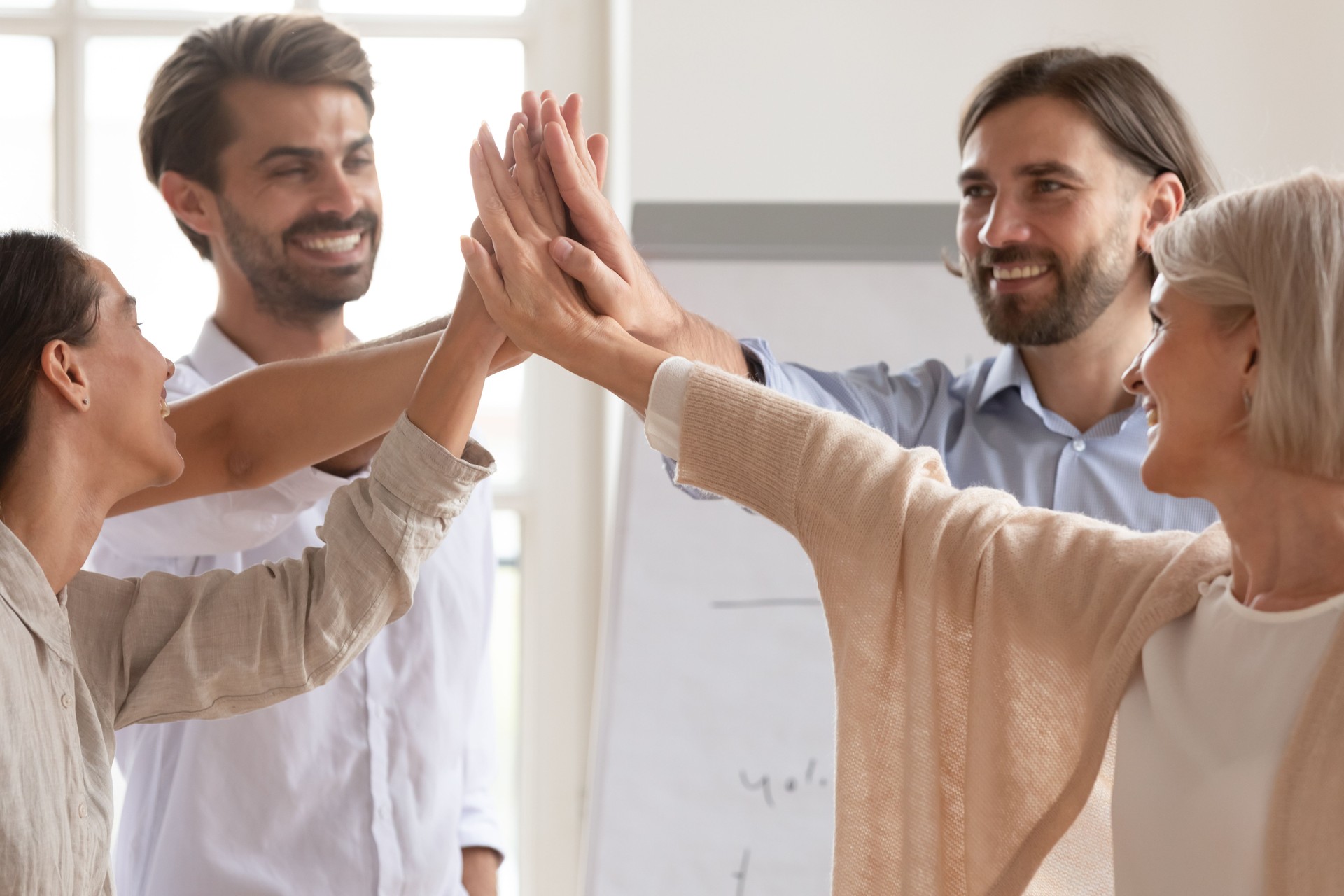 Los empleados felices del equipo de la empresa dan cinco altos que se unen